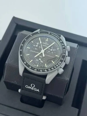 Omega x Swatch Speedmaster Moonswatch - Snygg Omega x Swatch Speedmaster Moonswatch med svart urtavla och tachymeterbård. Klockan har vita visare och index, samt svart textilband med Omega-logga. Perfekt för dig som gillar klassisk och sportig stil.