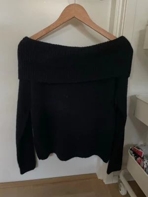 Marinblå off shoulder stickad tröja - Trendig marinblå stickad tröja med bred off shoulder-krage och långa ärmar. Perfekt för dig som vill ha en stilren och bekväm look. Mjuk och stretchig kvalitet som passar till många outfits.