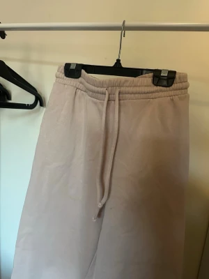 Beige mjukisbyxor med dragsko - Säljer ett par beige mjukisbyxor med resår i midjan och dragsko för skön passform. Byxorna har raka ben och sidofickor, perfekta för chill dagar. Materialet är mjukt och känns riktigt bekvämt mot huden.