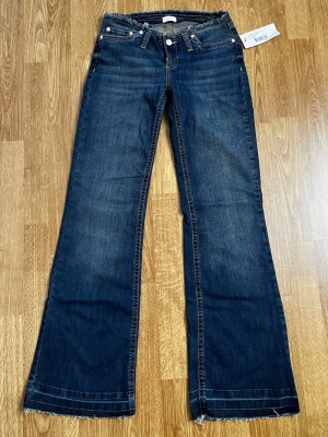 Nya lågmidjade jeans - Snygga helt nya populära mörkblå lågmidjade utsvängda jeans från Nelly i storlek 34. Modellen heter No Waist Bootcut Jeans