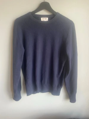 Mörkblå cashmere tröja Soft Goat - Säljer en mörkblå stickad tröja från Soft Goat i 100% cashmere. Tröjan har rund hals, långa ärmar och ribbade muddar vid ärmslut och nederkant. Perfekt för dig som gillar stilrena och mjuka plagg.