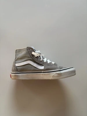 Gråa Vans Sk8-Hi sneakers - Säljer ett par gråa Vans Sk8-Hi sneakers med vit sula och klassisk vit sidestripe. Skorna har högt skaft och är tillverkade i mocka och canvas. Dock kommer inte skosnören med❗️