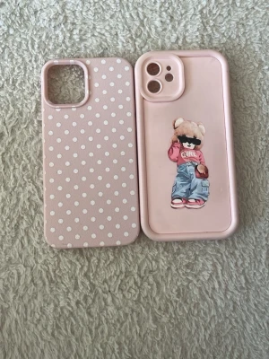 Två rosa mobilskal med mönster, iPhone 12 - Säljer två rosa mobilskal. Ett har vita prickar och det andra har en cool björn med solglasögon och jeans. Båda är gjorda i mjukt silikonmaterial och har öppningar för kamera och knappar. Perfekt för dig som vill ha ett gulligt och trendigt skydd till mobilen.