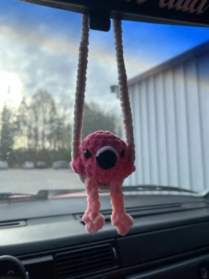 Virkad car hanger flamingo - Virkad ”car hanger” med en gungande flamingo som är cirka 9cm lång med benen🦩 Perfekt att ha i bilen eller hemma som dekoration☺️