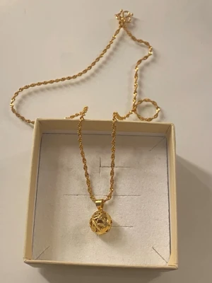 18K Guldpläterad halsband  - Snyggt halsband i Guldpläterad med ett tvinnat kedjemönster och ett klotformat hänge med öppen design. Perfekt för dig som gillar unika detaljer och vill sticka ut lite extra. 
