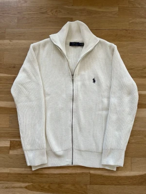 Polo Ralph Lauren cardigan - En stilren och snygg tröja i mycket fint skick, endast använd några få gånger och känns nästan som ny. Den har inga fläckar, slitningar eller andra skador.  Materialet är tjockt och varmt, vilket gör den perfekt för kallare dagar under höst, vinter och vår. Den fungerar lika bra till en mer elegant outfit som till en avslappnad vardagsstil.  * Storlek: M * Passform: Normal  * Skick: Väldigt bra, nära nyskick  Skriv gärna om du har frågor eller är 