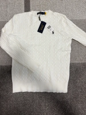 Polo Ralph Lauren tröja vit -  vit tröja från Polo Ralph Lauren med rund halsringning och lång ärm. Klassisk broderad logga på bröstet i svart. Tröjan har ribbade muddar vid ärmslut och nederkant. Perfekt för dig som gillar stilren och tidlös design.