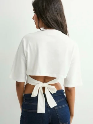 Vit croppad topp med knyt i ryggen - Säljer en vit croppad topp med korta ärmar och snygg knytning i ryggen. Toppen har en öppen rygg och är tillverkad i mjuk bomull, perfekt för dig som vill ha en trendig och bekväm look.