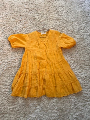 Gul kort klänning från Zara - En orange supersöt klänning från Zara som är perfekt till sommaren! i storlek 140, men skulle säga att den passar som 146 också. Den ser gul ut i kameran men i verkligheten är den en ljusare orange. Pris kan diskuteras