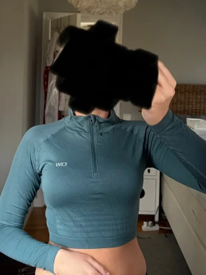  Långärmad topp ICIW - Snygg blå/grön croppad långärmad topp från ICIW med half zip framtill. Tight passform och sportig design, perfekt för dig som gillar stilrena träningskläder. Materialet känns stretchigt och följsamt. Tröjan är i storlek s och i bra skick