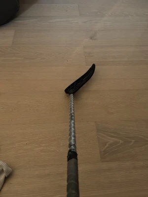 Silver innebandyklubba från Unihoc - Säljer en innebandyklubba från Unihoc med silverfärgat skaft och svart blad. Endast använt på 2 matcher och några träningar inga skador på de eller nåt!Skaftet har ett mönster och bladet är böjt med öppet nätmönster. Perfekt för dig som gillar innebandy och vill ha en snygg klubba.