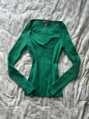 Turkos ribbad topp från H&M - Snygg turkos ribbad topp från H&M med lång ärm och v-ringad halsringning. Toppen har en tight passform och är tillverkad i stretchigt material. 