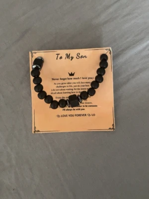 Svart pärlarmband till din son  - !! KAN PRUTA!! Säljer ett svart armband med runda pärlor och några större dekorativa pärlor. Armbandet kommer på ett kort med texten 'To My Son' och ett inspirerande budskap. Perfekt som present till någon speciell. Materialet är troligen plast eller sten. Aldrig använt armbandet 