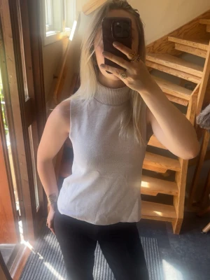 Ljusgrå ärmlös polotopp - Säljer en stilren ljus beige polotopp i stickat material. Toppen är ärmlös med hög polokrage. Helt ok skick, liten reva (se bild 4), märks inte men kan sy ihop om det önskas. Från Zara i storlek S🌸