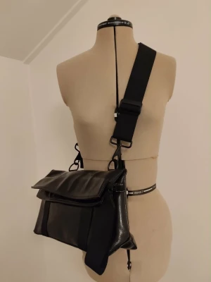 Cool trendig crossbody väska från Hope i svart lack  - Svart väska i ett lack tyg från Hope. Endast något använd så k mycket bra skick. Nypris 1700:-