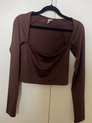 Brun croppad topp från NLY Trend - Säljer en brun croppad topp med square urringning från NLY Trend. Toppen har en tight passform och är tillverkad i ett mjukt, stretchigt material som känns skönt mot huden. Perfekt för dig som gillar trendiga och stilrena plagg. Endast testad aldrig använd, har dock tvättat den.