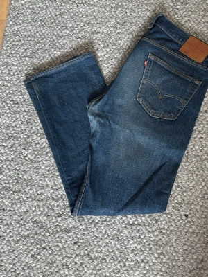 Mörkblåa Levis 501 jeans - Tjena! Säljer ett par tvär feta 501 från Levis. Perfekt som basplagg till garderoben. Är dock lappade i grenen men märks inte vid användning. Har ni några funderingar är det bara att skriva! Priset är ej skrivet i sten.