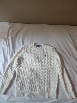 Ralph Lauren stickad tröja  - Ralph Lauren stickad tröja i krämvit färg, storlek L. Använd ett fåtal gånger och i mycket fint skick. Säljes då den inte kommer till användning. Kan skicka video när jag visar att jag skannar tröjan till Ralph Laurens hemsida. Hör av dig vid intresse eller om du vill ha fler bilder.. 