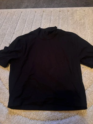 Svart turtle neck tshirt - En kort t shirt med liten turtle neck och lite tjockare material knappt använd.