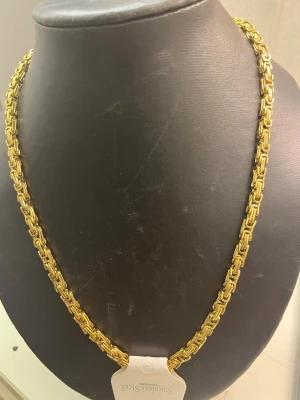 Guldfärgat halsband i rostfritt stål - Snyggt guldfärgat halsband med robust kedjedesign i rostfritt stål. Halsbandet har en modern, fyrkantig länkstruktur som ger ett stilrent och trendigt intryck. Perfekt för dig som vill ha ett statement-smycke som sticker ut.