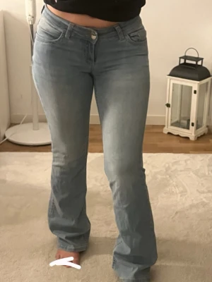 Ljusblå bootcut jeans från Nelly  - Säljer ett par ljusblå bootcut jeans med snygg rosa broderad detalj på bakfickorna från Nelly . Super stretchiga och sköna, storlek 36. Skriv gärna om du vill ha en bättre bild på dom!