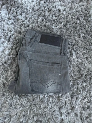 Replay anbass jeans - Snygga grå jeans från Replay med klassisk femficksdesign och diskret logga på fickan. Jeansen har en stilren look och passar perfekt till många olika outfits. Tillverkade i mjuk bomullsmix för skön passform. Replay anbass hyperflex jeans.