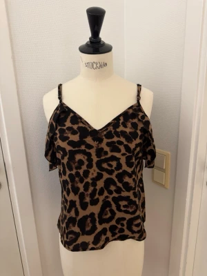 Leopardmönstrad topp 🐆 - Snygg lätt blus med leopardmönster i brunt och svart, offshoulder med tunna axelband och v-ringning. Luftigt tyg som känns skönt mot huden. Skickas eller hämtas på Hägerstensåsen i Stockholm 🐆