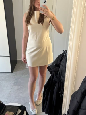 Kort ljus klänning med ärmlös design - Snygg och stilren kort klänning i ljus beige färg med ärmlös design och rund halsringning. Klänningen har en rak passform och är perfekt för dig som gillar minimalistisk stil. Materialet känns mjukt och bekvämt mot huden. Klänningen är helt ny och med lappen kvar:) pris går o diskutera 