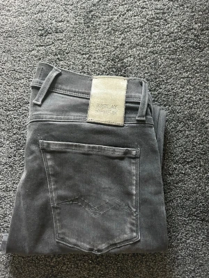 Replay svarta - Säljer ett par svarta jeans från Replay med stretchigt material och klassisk femficksdesign. Jeansens bakficka har en diskret broderad detalj och märkespatch i beige på linningen. Perfekt för dig som gillar en modern stil 
