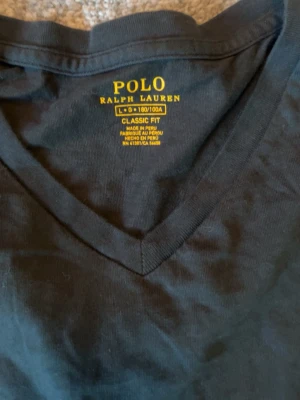 Svart   t-shirt från  Polo Ralph Lauren - Klassisk svart t-shirt från Polo Ralph Lauren röd broderad logga på bröstet. Tillverkad i mjuk bomull och har en normal passform. Perfekt för en clean och stilren look.