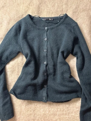 Mörkblå kofta med knappar - Mysig mörkblå kofta från H&M med rund halsringning och knäppning framtill. Koftan har långa ärmar och är tillverkad i ett mjukt, stickat material. Perfekt att slänga på sig när det är lite kyligare ute.