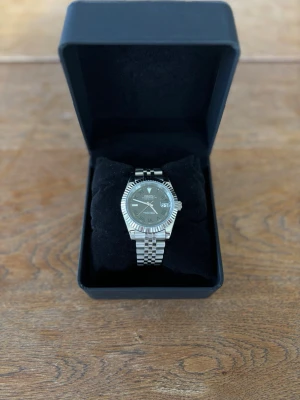 Seiko mod Wimbledon - Stilren 40mm Seiko mod datejust wimbledon i silverfärgat stål med klassisk länkarmband och räfflad bezel. Urtavlan är grå med gröna romerska siffror och datumvisning vid klockan tre (Wimbledon urtavla). Perfekt accessoar för dig som gillar tidlös design.                                            Får med låda! 🗃️                                                     Pris ej hugget i sten! 🪨 