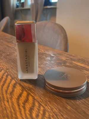 Anastasia Beverly Hills foundation - Flytande foundation från Anastasia Beverly Hills i en elegant glasflaska med silvrigt lock. Färgen är ljus och passar dig med ljus hudton. Medföljer även en rund puderburk i matchande design med Anastasia-loggan på locket.