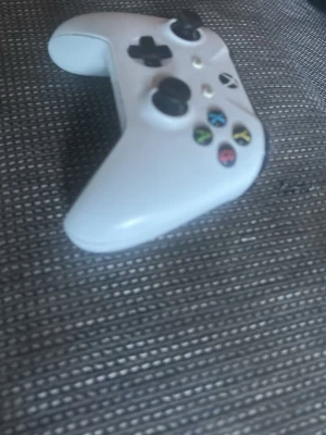 Vit Xbox  handkontroll - Säljer en vit Xbox One handkontroll med klassisk design, svarta styrspakar och färgade knappar. Perfekt för gaming på konsol eller PC. Tillverkad i tålig plast och har en skön ergonomisk form som ligger bra i handen.