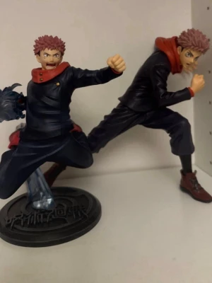 Jujutsu Kaisen Yuji Itadori figurer - Två detaljerade figurer av Yuji Itadori från Jujutsu Kaisen. Båda figurerna har mörkblå kläder med röda detaljer och röd huva, samt bruna skor. Perfekt för anime-samlaren eller som dekoration i hyllan. Ingen låda tyvärr 💞 jjk