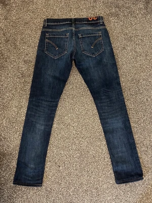 Mörkblå skinny jeans från Dondup - Snygga mörkblå skinny jeans från dondup med klassiska bakfickor och kontrastsömmar. Jeansen har en smal passform och är tillverkade i ett stretchigt denimtyg som sitter tajt längs benen. Perfekta för en trendig och avslappnad stil.