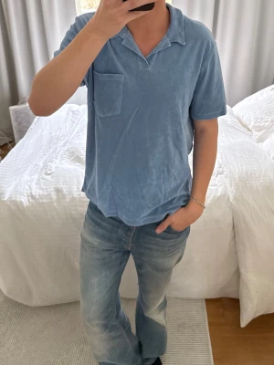 Ljusblå frottétröja med krage - Ljusblå tröja i mjuk frotté med klassisk krage och bröstficka. Kortärmad och avslappnad passform som ger en chill vibe. Perfekt för dig som gillar bekväma och stilrena plagg.