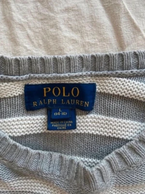 Randig långärmad tröja från Polo Ralph Lauren - Säljer en fin långärmad och randig tröja från Polo Ralph Lauren i ljusgrått och vitt. Tröjan har rund halsringning och ribbade muddar vid ärmslut och nederkant. Storlek L i barnstorlek 14-16 