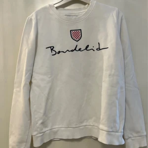 Vit sweatshirt från Bondelid - Säljer en stilren vit sweatshirt från Bondelid med deras logga tryckt på framsidan. Tröjan har långa ärmar och en rund halsringning, perfekt för en avslappnad look. Passar bra till både jeans och joggers.