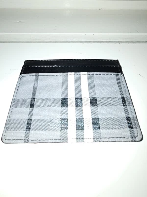 Burberry plånbok - Snyggt kortfodral med klassiskt rutmönster i svart, grått och vitt. Fodralet har flera kortfack och är tillverkat i ett tåligt material som liknar konstläder. Perfekt för dig som vill ha ett stilrent och smidigt sätt att bära dina kort.
