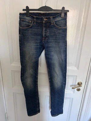 Nudie Jeans Dude Dan - Snygga blå slim fit jeans från Nudie Jeans med klassisk femficksdesign och orangea sömmar. Jeansen är i modellen Dude Dan, en av de utan tvekan snyggaste Nudie modellerna genom tiderna. Strlk: W:28 L:32
