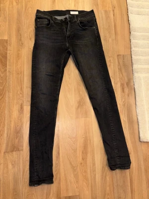 Tiger of Sweden jeans - Säljer ett par svarta jeans från tiger of sweden med klassisk femficksdesign. Jeansen har smal passform, normal midja och diskreta slitningar framtill. Perfekta till en avslappnad streetstil. Materialet är troligtvis bomull med elastan för extra komfort. 