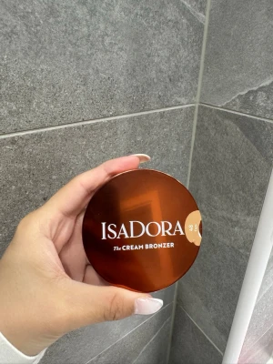 Isadora The Cream Bronzer 48 Tan - Snygg bronzer från Isadora i nyansen 48 Tan. Kommer i en rund, brun kompakt dosa med spegel. Krämig formula som ger en naturlig solkysst look. Perfekt för att framhäva ansiktskonturer och ge glow. Vegansk och parfymfri. Använd 2 gånger!!!! 