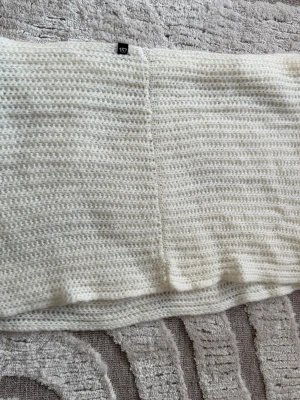 Vit stickad halsduk från Lager 157 - Säljer en vit stickad halsduk från Lager 157 med grovt ribbat mönster. Halsduken är mjuk och har en enkla, rektangulär form. Använd ett fåtal gånger. 