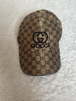 Keps  - Kepsen är i färgen Bronz och säljs inte mer. Den är inte äkta. Den har rödgröna stripes på sidorna.