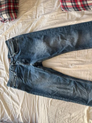 Blå jeans från Morris - Snygga blå jeans från Morris med klassisk femficksdesign och diskret slitning på låren. Jeansen har normal midja och raka ben. Tillverkade i denim med detaljer i silverfärgad metall. Perfekta för en avslappnad och trendig look. Finns inga defekter eller tecken på mycket användning.