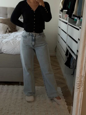 Ljusblå raka jeans med hög midja - Säljer ett par ljusblå jeans med rak passform och hög midja. Jeansen har klassisk femficksdesign och är tillverkade i ett mjukt denimtyg. Perfekta för en avslappnad och trendig look.