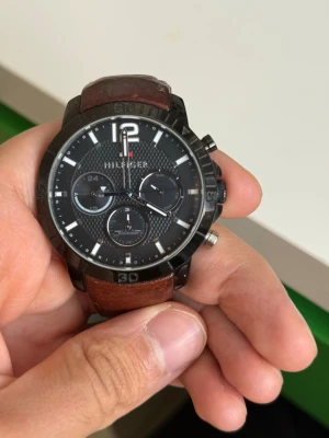 Tommy Hilfiger herrklocka brun/svart - Stilren klocka från Tommy Hilfiger med svart urtavla, vita detaljer och brunt läderarmband. Klockan har flera små urtavlor och robust boett i metall. Perfekt accessoar för dig som vill ha en klassisk men modern look. Klockan behövs en ny batteri bara 