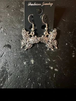 Silvriga fjärilsörhängen - Unika örhängen i silverfärgad metall med detaljerade fjärilar. Hängande modell med krok, perfekt för dig som gillar statement-smycken och vill sticka ut. Snyggt mönstrade och lätta att matcha med olika stilar.