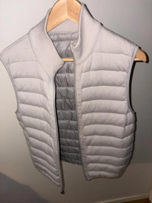 Falconeri dunväst - Stilren vit dunväst med quiltat mönster och hög ribbad krage. 100% puro cashmere. Perfekt att slänga över en hoodie eller tröja för extra värme. Materialet är mjukt och lätt, vilket gör den enkel att bära. Den kan användas in och ut med två olika typer av färgerr. Knappt använd och orginal pris 3300kr men säljs ej längre i just den vita färgen. Skriv om du har extra frågor!! Litet spricka som är sydd på baksidan men knappt syns